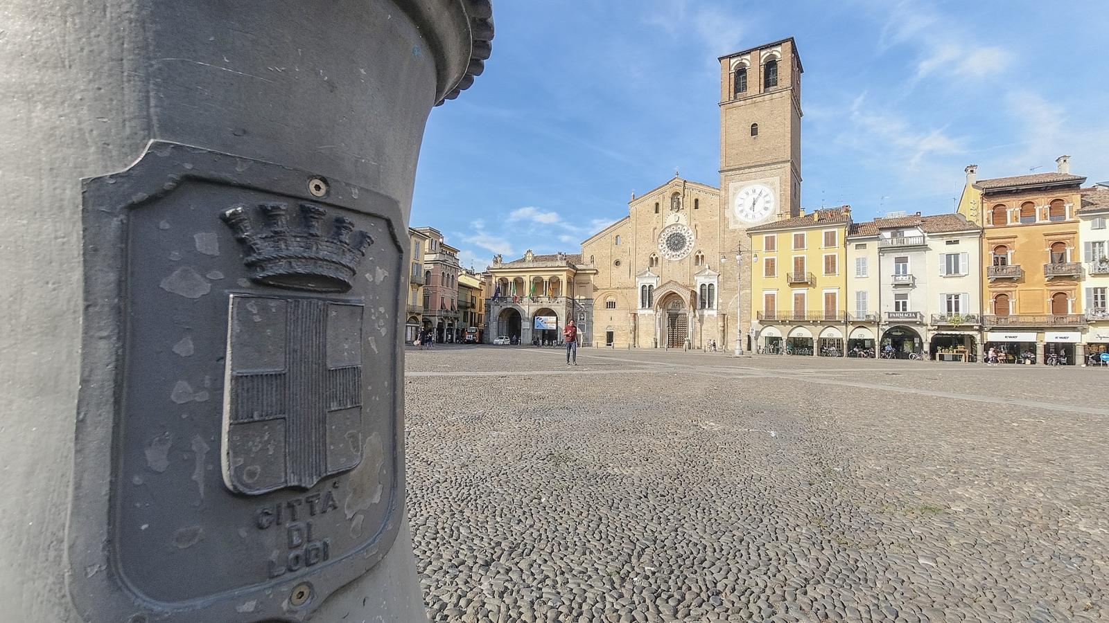 Piazza della Vittoria a Lodi con il Duomo, dietro un lampione con lo stemma della città