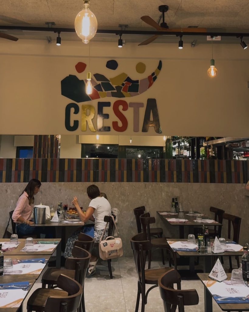 Sala interna di Cresta con sedie in legno e piastrelle colorate alle pareti