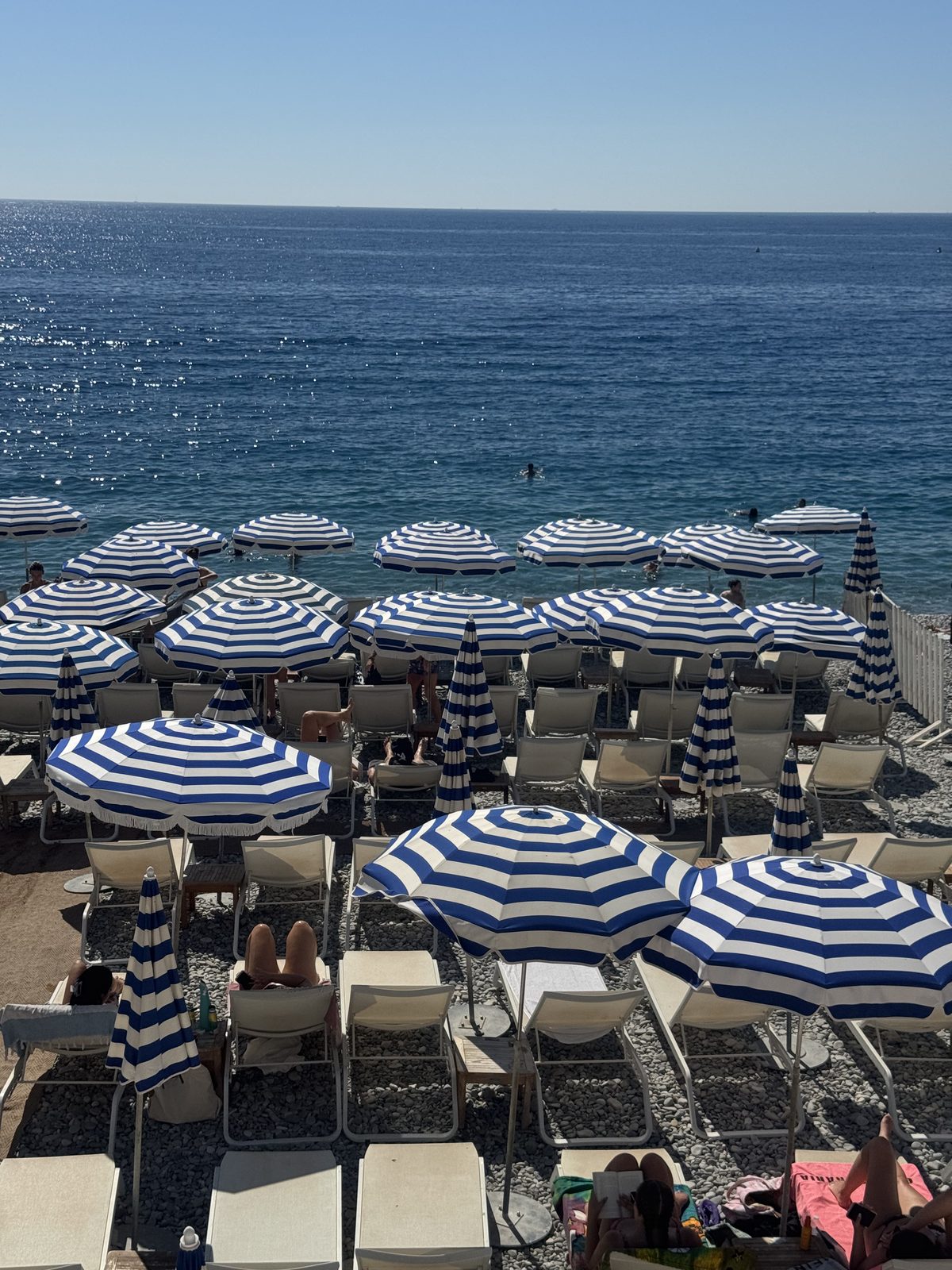 Gli iconici ombrelloni a righe blu e bianche sulla spiaggia di Nizza, lungo la Baie des Anges