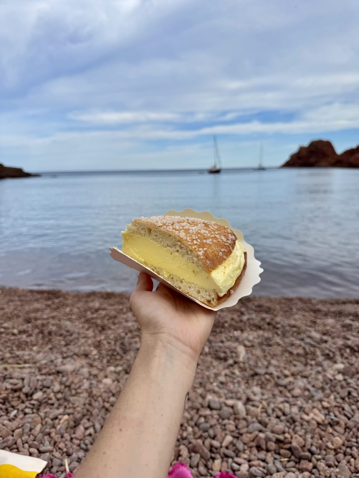 Una fetta di Tarte Tropézienne, la brioche farcita tipica di Saint-Tropez, davanti al mare