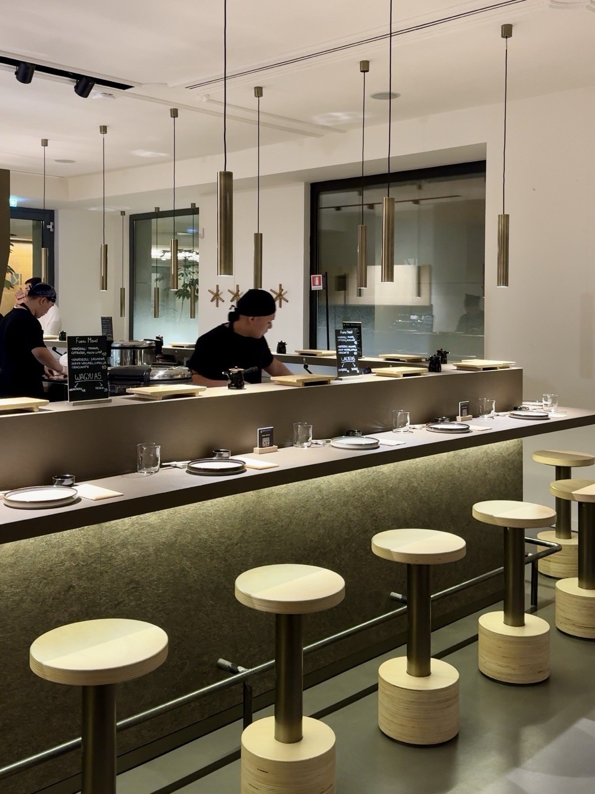 Il bancone dell'handroll bar Nippoteka a Milano, con gli sgabelli e gli chef al lavoro