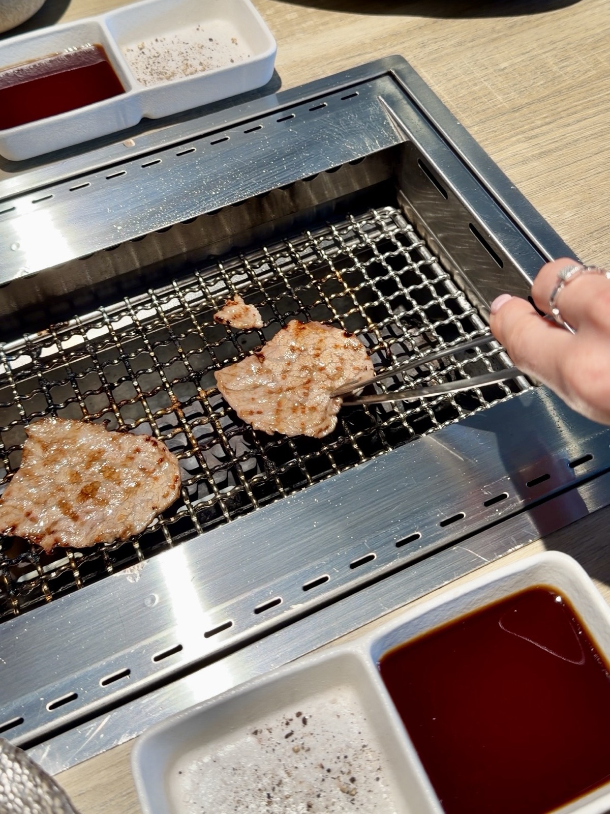 Griglia integrata al tavolo con la carne in cottura da Yakiniku KE a Milano