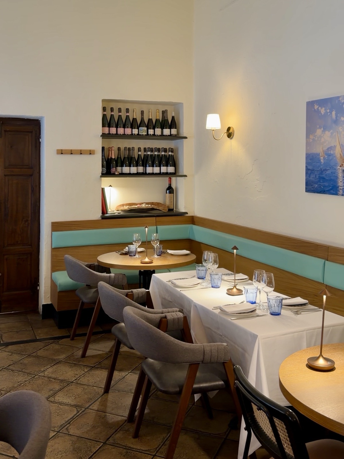Sala di Hostaria Mediterraneum a Milano con pareti bianche, tavoli in rovere e dettagli azzurri