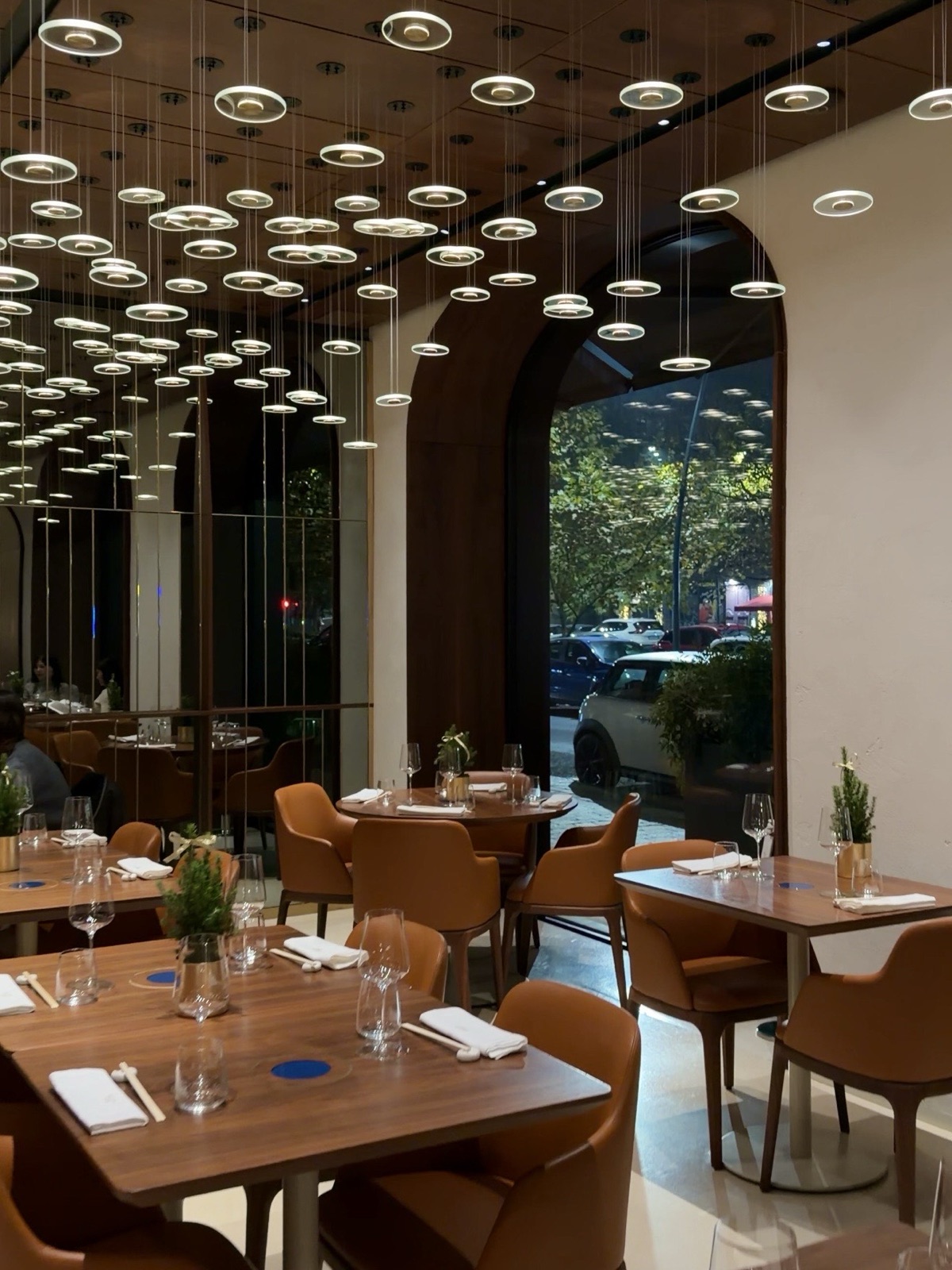 Tavoli in legno e sedute color cuoio nella sala di Izu a Milano