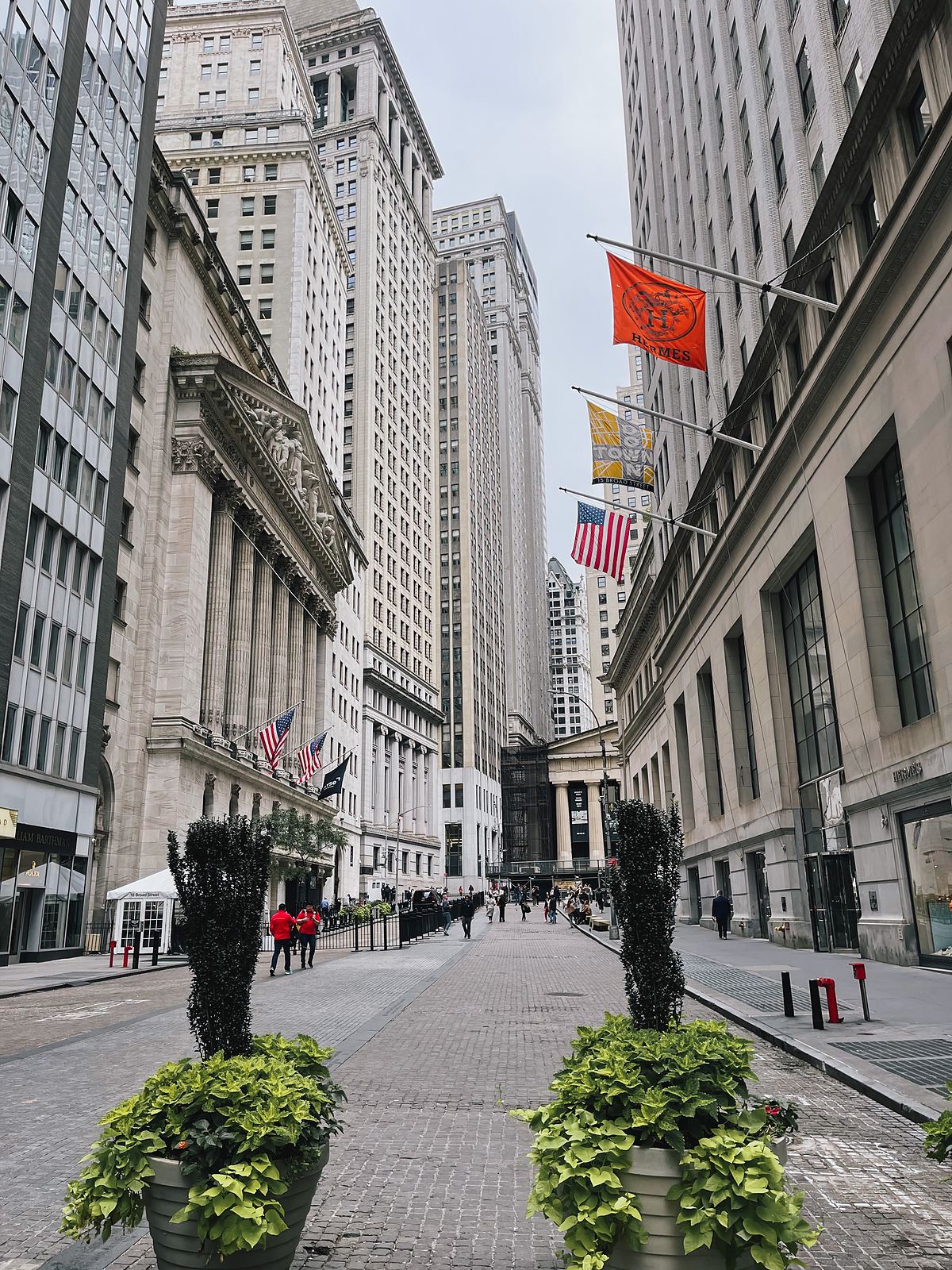 Wall Street con la facciata del New York Stock Exchange e le bandiere americane