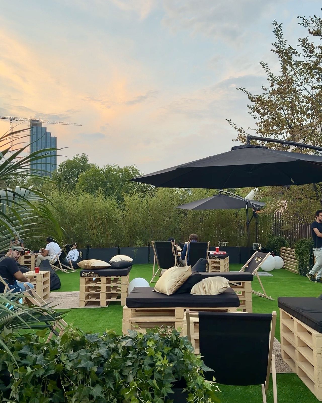 L'area relax del Coca-Cola Pizza Village di Milano al tramonto, con sdraio, pouf e divani di pallet sul prato