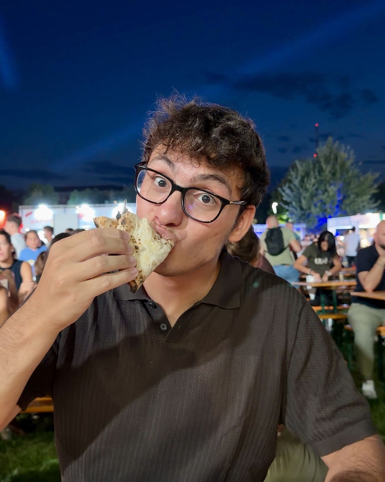Gianmaria mangia una pizza a portafoglio ai tavoloni del Coca-Cola Pizza Village di Milano