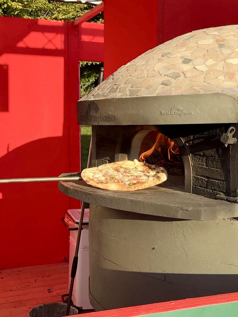 Pizza in cottura nel forno a legna di uno stand del Pizza Village di Milano