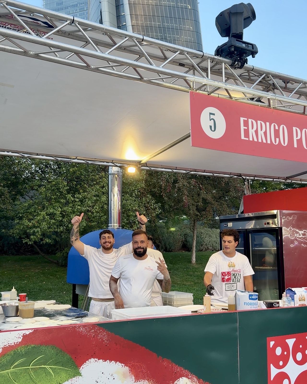 I pizzaioli sorridenti dietro il banco di uno stand del Coca-Cola Pizza Village di Milano