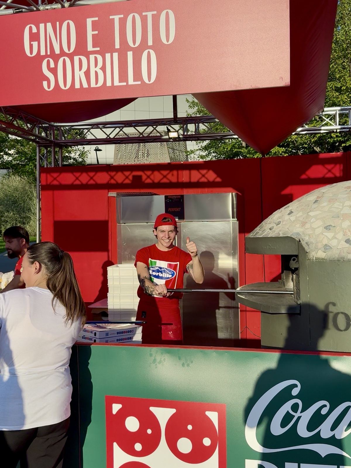 Pizzaiolo sorridente al lavoro dietro il banco del Coca-Cola Pizza Village di Milano