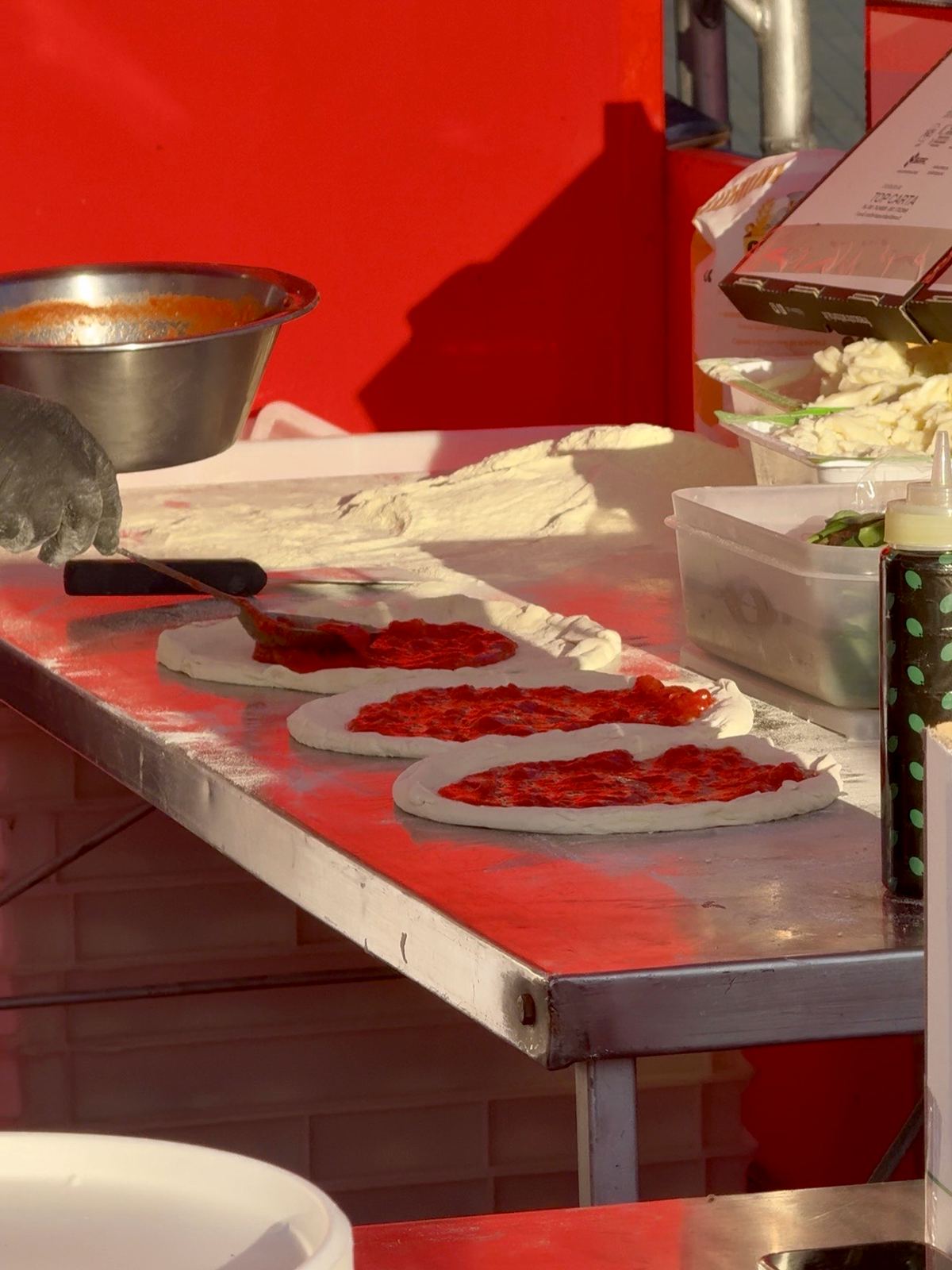 Pizze in preparazione sul banco di una pizzeria del Coca-Cola Pizza Village di Milano