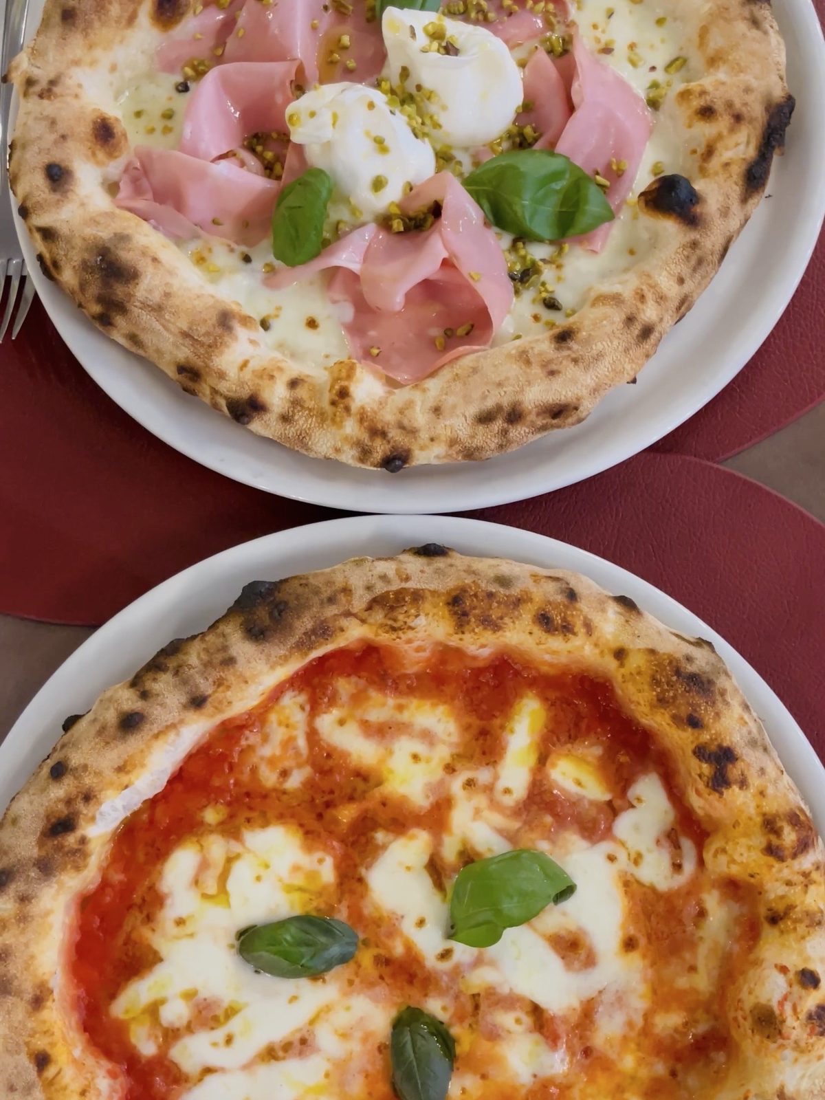 Due pizze di AmaLe a Muggiò servite al tavolo, margherita e pizza gourmet con mortadella