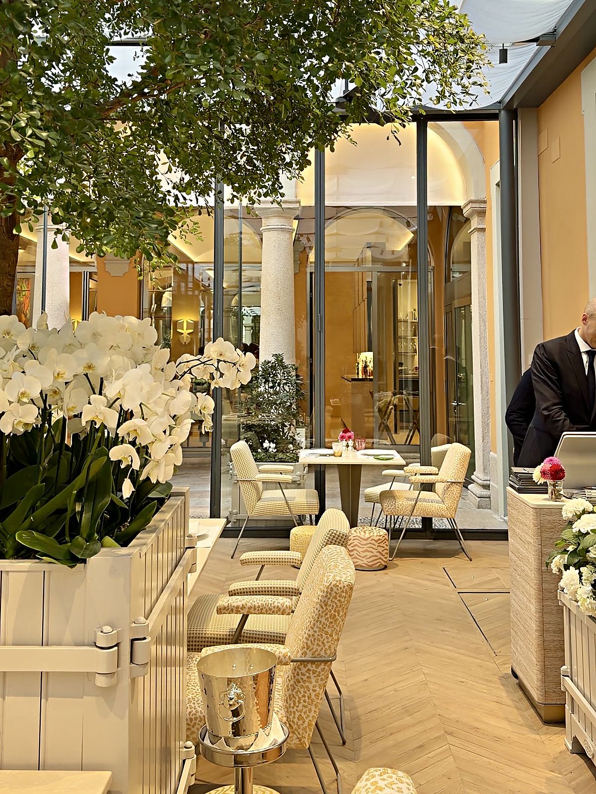 Veranda vetrata di Monsieur Dior a Milano con orchidee bianche e poltroncine leopardate