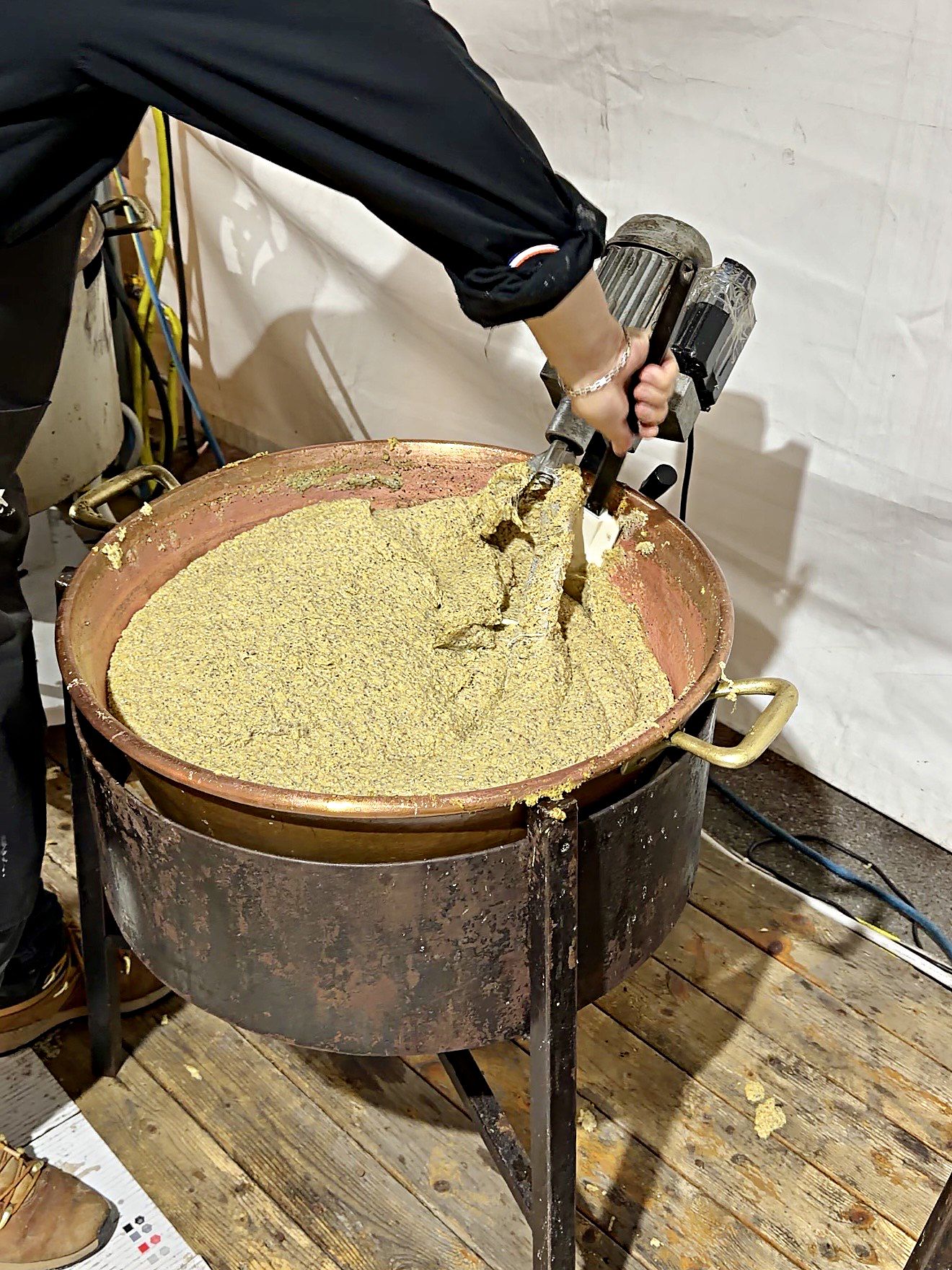 Un volontario rimesta la polenta taragna nel paiolo di rame con il mescolatore elettrico