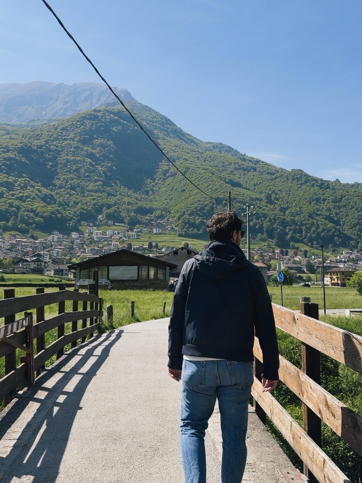 Giamma cammina sulla ciclopedonale con le casette di montagna sullo sfondo