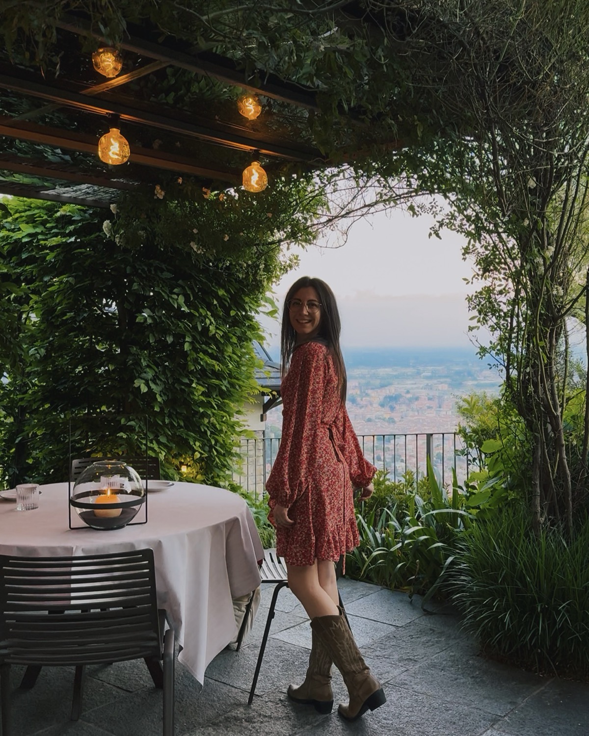 Ludovica al tavolo esterno del Relais San Vigilio con vista panoramica sulla pianura di Bergamo